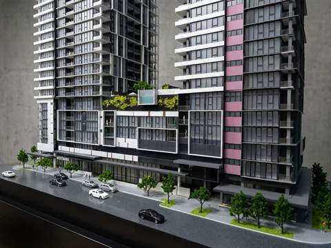 Maquette van een woontoren met een daktuin, aan een straat met auto's en bomen