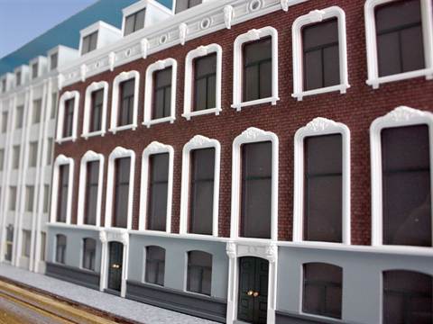 Maquette van een historische bakstenen gevel met witte raamomlijstingen