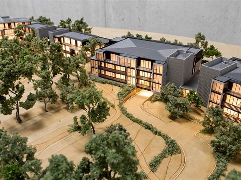 Maquette van een woonwijk met appartementengebouwen tussen bomen en slingerende paden