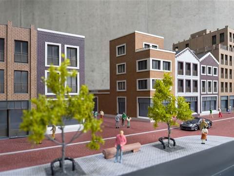 Maquette van een Nederlandse straat met bakstenen woon- en winkelpanden, trapgevels, bomen en figuren