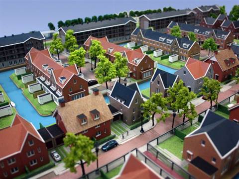 Maquette van een woonwijk aan het water met bakstenen woningen en tuinen