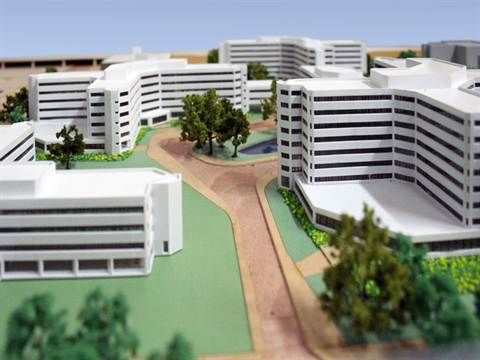 Maquette van witte gebouwen rond een groen plein